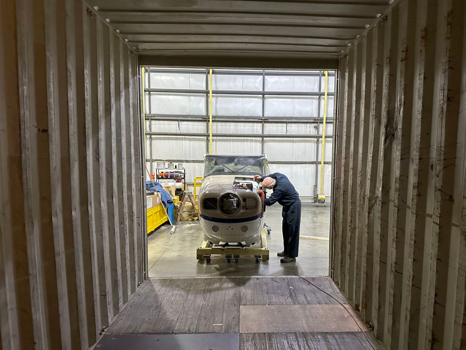 Loading the fuselage of a Cessna U206F into a container for shipping to Papua New Guinea.